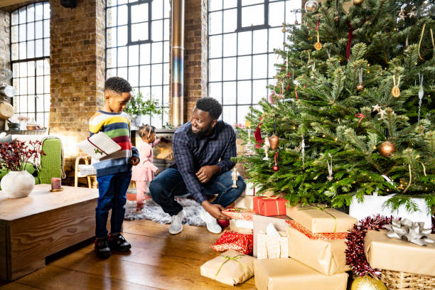 Mid adult father and son looking at gifts under holiday tree
