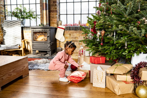 Curious Black toddler examining gifts under holiday tree