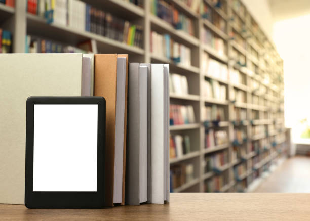 istock Hardcover books and modern e-book on wooden table in library. Space for text 1466757849