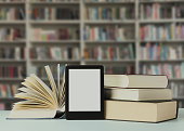 Hardcover books and modern e-book on table in library