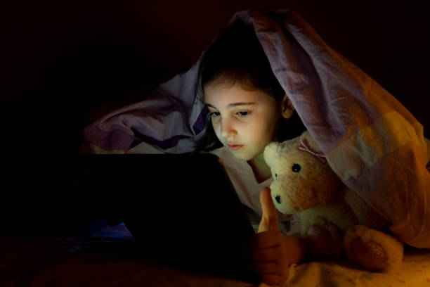 istock Little girl using digital tablet in her bed at night 1466761837