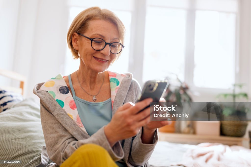 Woman reads about Hormone replacement therapy A woman using her phone to find some information about hormone replacement therapy Applying Stock Photo