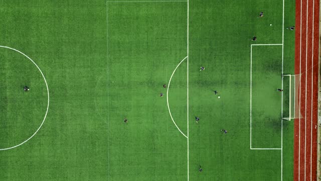 soccer players training on green grass soccer field, aerial view