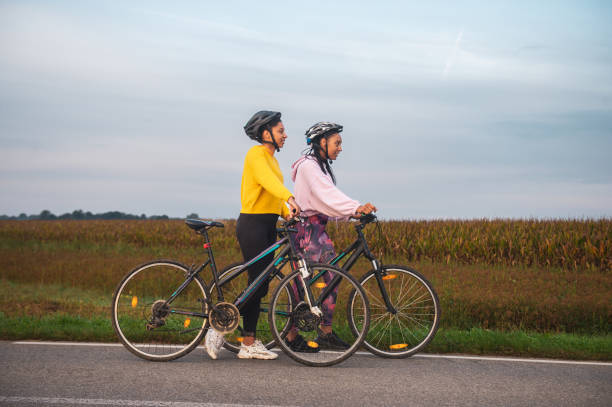istock Female athletes with bicycles walking on road by landscape 1466765709