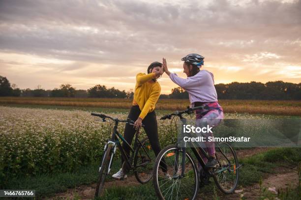 Athletes Giving High Five While Riding Bicycles On Dirt Road Stock Photo - Download Image Now