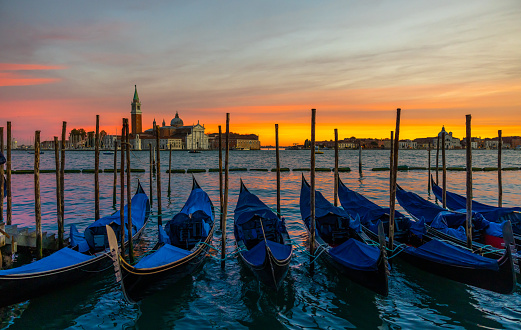 Gondolas moored side by side on Grand Canal with beautiful view of Church of San Giorgio Maggiore against sky during sunset at Venice,Italy