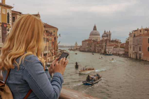 istock Woman using smart phone on footbridge over Grand Canal 1466766429