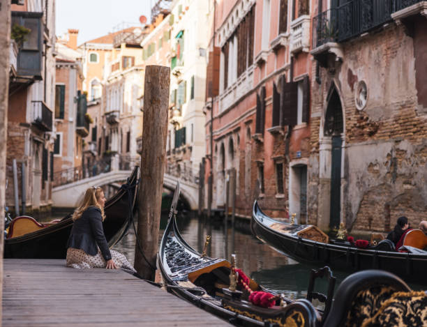 istock Woman sitting on pier by gondolas on Grand Canal 1466766437