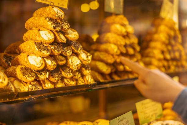 frau zeigt auf cannolis, die in vitrine angeordnet sind - cannoli italian culture ricotta dessert stock-fotos und bilder