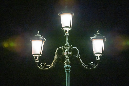 Low angle view of illuminated vintage street lamp glowing against sky at night