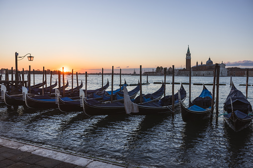 Gondolas moored side by side at harbor on Grand Canal against Church of San Giorgio Maggiore under clear sky during sunset at Venice,Italy