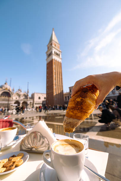 istock Man's hand with croissant and coffee at St. Mark's Square 1466766797