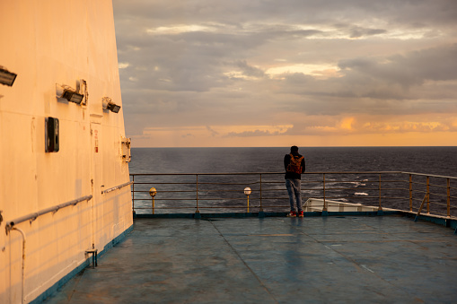 Rear view of man standing on deck looking at sea view while traveling in cruise during vacation