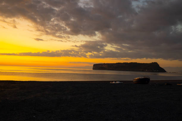 Scenic view of island surrounded with sea in front of cloudy sky during sunset