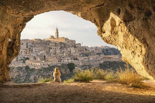 Rear view of woman looking at historic city while sitting at cave on sunny day during vacation
