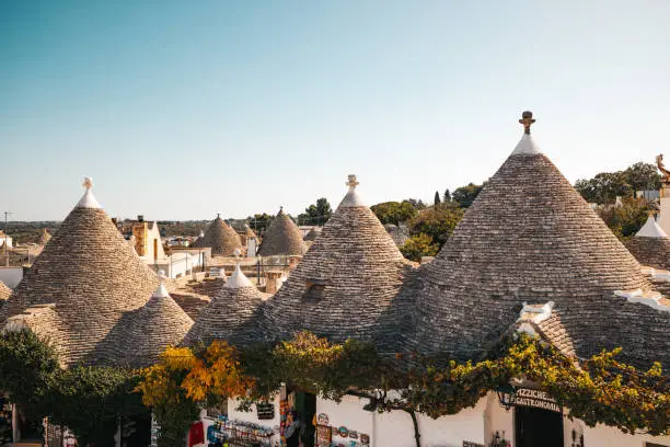 Trulli houses with conical roofs in old town against clear sky