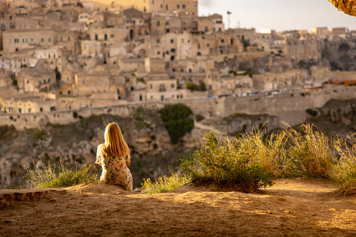 Rear view of female tourist looking at historic city while sitting on ground during sunny day