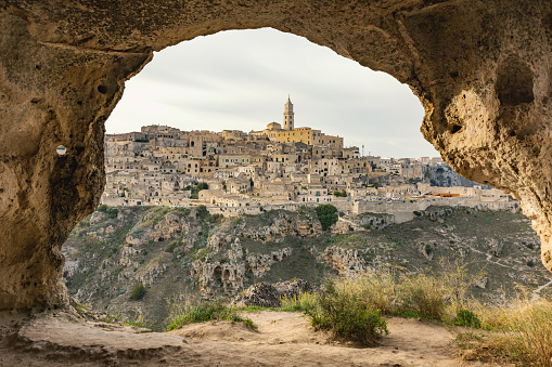 Historic buildings and towers in city on mountain seen from rock caves with sky in background