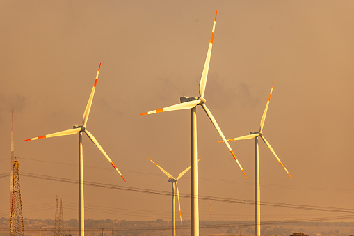 Tall wind turbines with clear sky in background during sunset