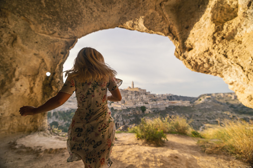 Rear view of carefree female tourist running in cave on sunny day during vacation
