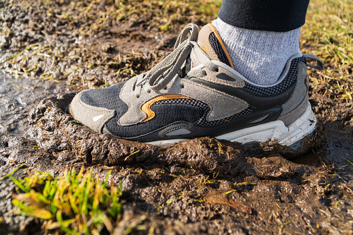 A man in sneakers runs on the ground. Sneakers in the mud. Modern sneakers.