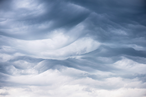 Fascinated wavy ridges of the rare asperitas clouds with dark blue textures and undulating ripples and waves of light. Natural phenomenon.