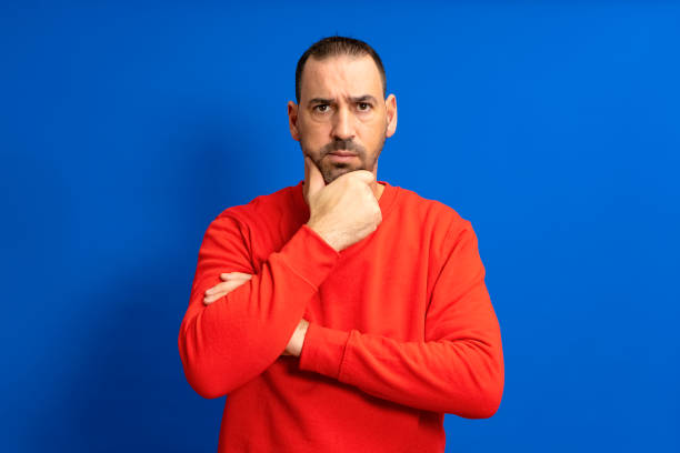 istock Bearded hispanic man wearing red sweater pensive thinking looking at copyspace hold hand chin isolated over blue color background. 1466776203