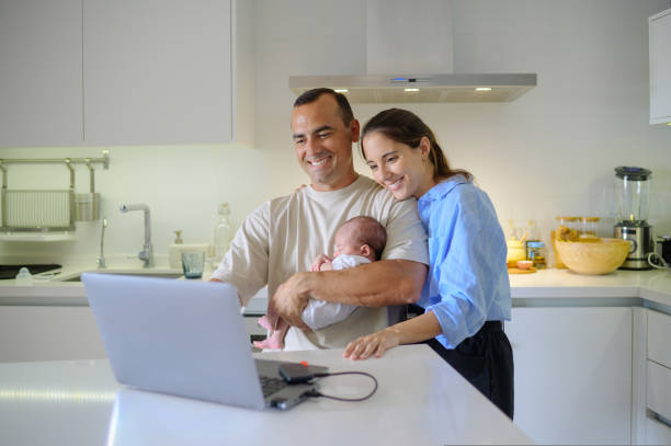 istock Happy parents with newborn child using laptop in kitchen 1466777844