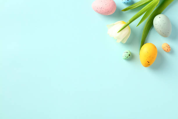istock Happy Easter concept. Colorful Easter eggs with tulips on light blue background. Flat lay, top view, copy space. 1466777962