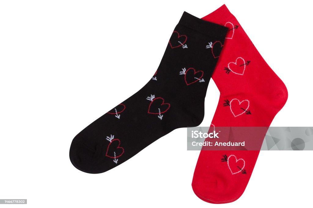 Duas meias, vermelhas e pretas, como se andassem, com desenhos de muitos corações, sobre um fundo branco - Foto de stock de Meia royalty-free