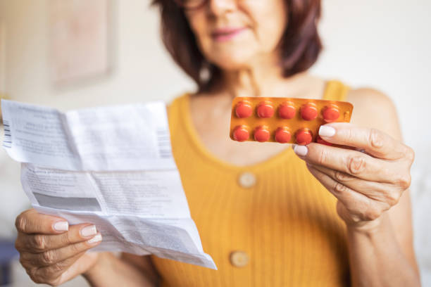 close up of a woman checking patient information leaflet for her medicine. - menopause imagens e fotografias de stock