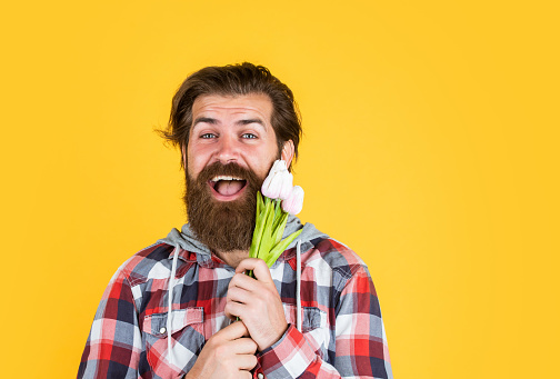 happy man with beard hold tulip flowers. fathers day concept. happy birthday gift. spring bouquet for her. ready for romantic date. present for womens day. celebrate mothers day.