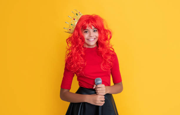 istock child smile in crown with microphone on yellow background 1466782168