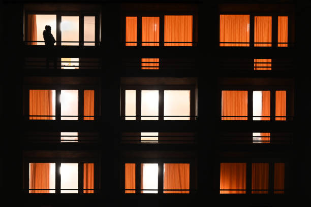 istock Apartment block windows at night wide with silhouette 1466782408