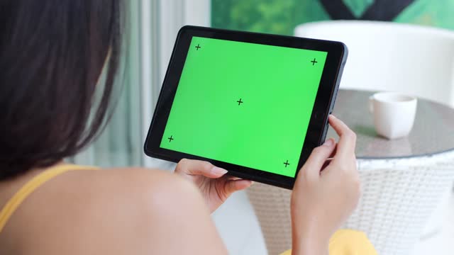 Woman using a tablet computer with green screen at home