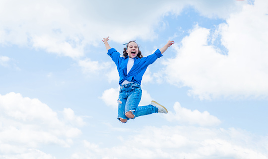 cheerful child jump in casual denim apparel outdoor, happiness.
