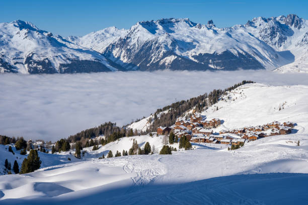 View of Plagne Soleil ski resort in French Savoy Alps. Snowcapped mountains, cloud inversion and apartment buildings stock photo