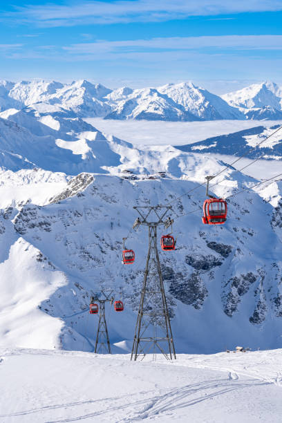 Red gondolas of cable car seen from Bellecote glacier, La Plagne ski resort, France,  in winter. Inversion clouds in valley stock photo