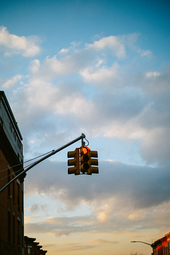 Traffic light in NYC against the cloudy sky.