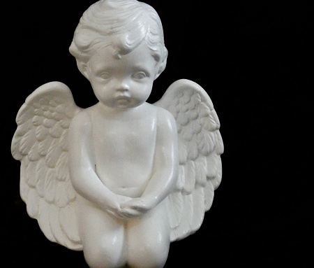 PRAYING PORCELAIN WHITE ANGEL - \nCHILD STATUE WITH WINGS ON BLACK BACKGROUND & COPY SPACE