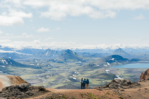 Back of three hikers admiring view of amazing landscape in Iceland while trekking famous Laugavegur trail