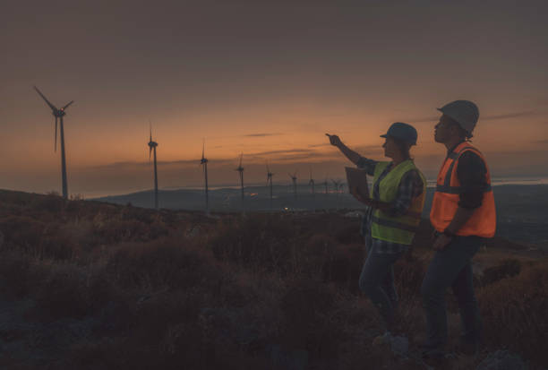 istock Young maintenance engineer team working in wind turbine farm at sunset 1466797658