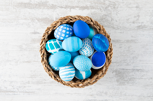 Easter eggs in a basket on white rustic background