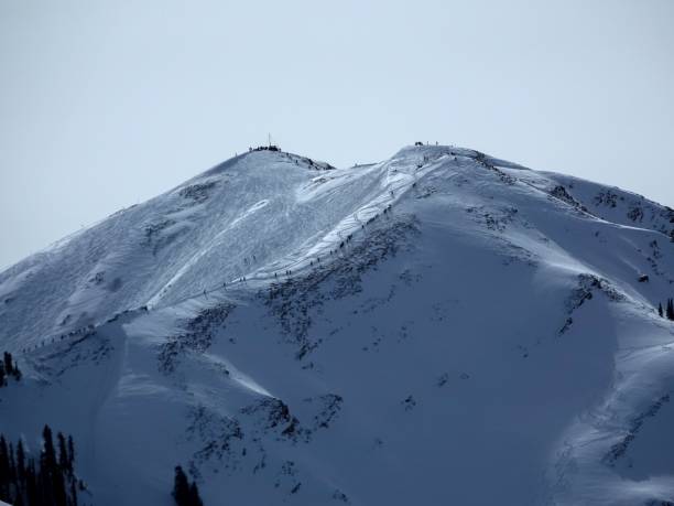 vue téléobjectif de dizaines de skieurs et de planchistes marchant jusqu’à 12392 pieds highland peak pour skier le bol. - aspen highlands photos et images de collection