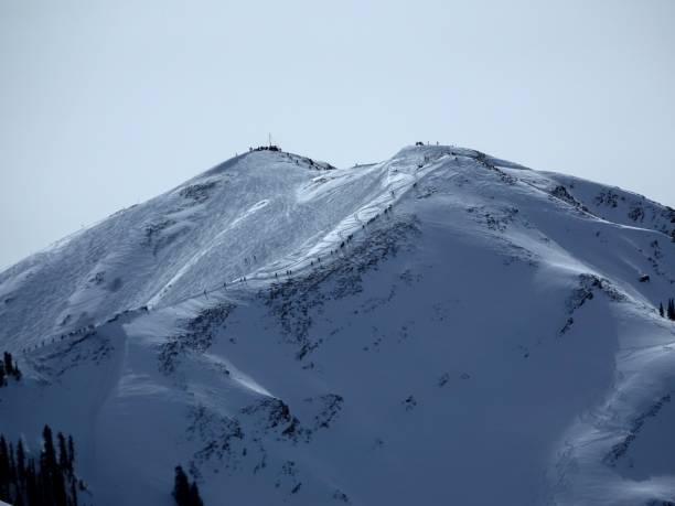 telephoto view of dozens of skiers and snowboarders hiking to 12392 foot highland peak to ski the bowl. - aspen highlands imagens e fotografias de stock