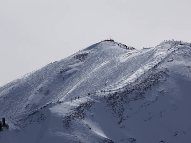 vue téléobjectif de dizaines de skieurs et de planchistes marchant jusqu’à 12392 pieds highland peak pour skier le bol. - aspen highlands photos et images de collection