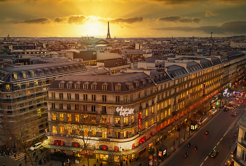 Paris, France  - February 2, 2023: Historic city center of Paris in the sunset, famous Eiffel Tower and Galleries Lafayette building (big, popular, modern shopping center was open in 1912).