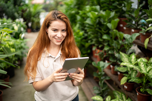Portrait of a young woman working using digital tablet in a garden center