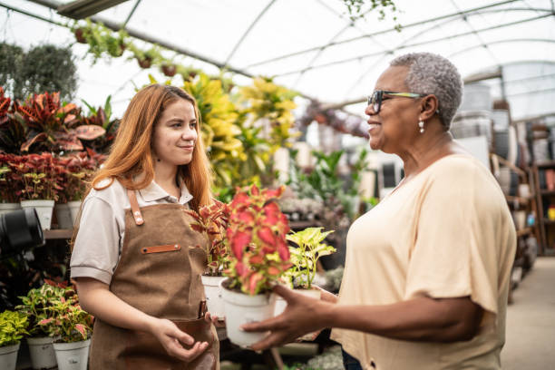 jovem vendedora ajudando cliente em um centro de jardim - florist flower market flower store - fotografias e filmes do acervo