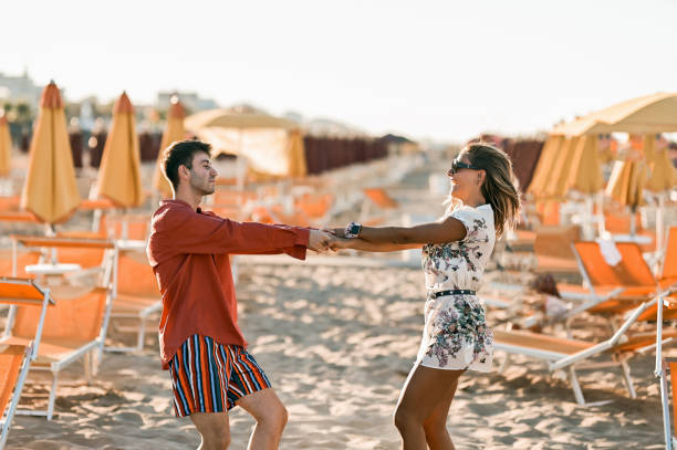 młodzi ludzie tańczą na plaży o zachodzie słońca. - beach couple satisfaction playing zdjęcia i obrazy z banku zdjęć